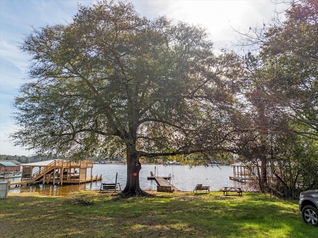 view of dock with a lawn and a water view