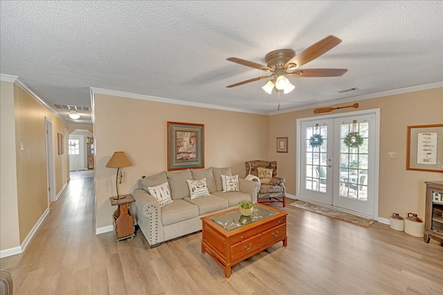 living room featuring ornamental molding, a textured ceiling, light wood-type flooring, and french doors