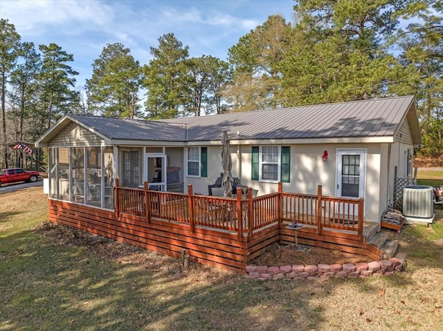 back of property with central AC, a yard, and a sunroom