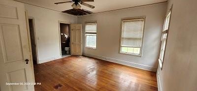 unfurnished bedroom with ceiling fan and wood-type flooring