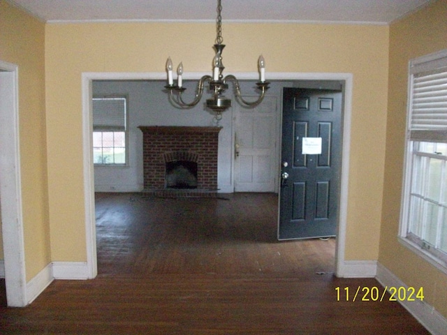 unfurnished living room with a chandelier and a brick fireplace