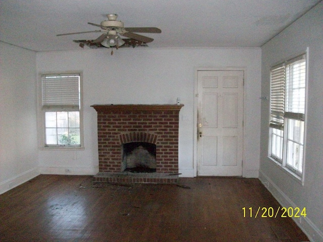 unfurnished living room with a fireplace, a healthy amount of sunlight, dark wood-type flooring, and ceiling fan