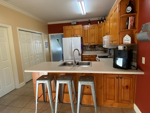 kitchen with a kitchen bar, white fridge, sink, ornamental molding, and light tile patterned floors