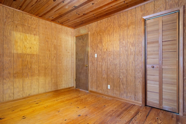 unfurnished bedroom featuring wooden walls, wooden ceiling, and wood-type flooring