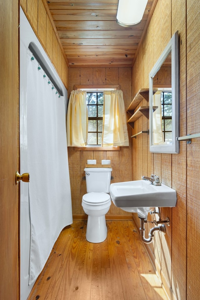 bathroom with wooden ceiling, hardwood / wood-style floors, toilet, and wood walls