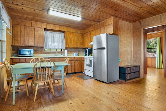 kitchen with light hardwood / wood-style floors, wooden ceiling, appliances with stainless steel finishes, and sink