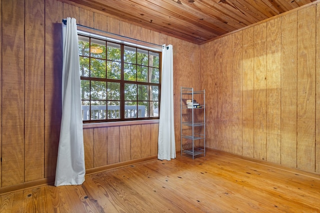 empty room with wooden ceiling, wood walls, and light wood-type flooring