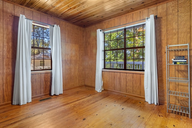 spare room with light wood-type flooring, wooden walls, and wooden ceiling