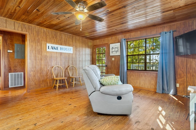 living area with electric panel, wooden walls, and light hardwood / wood-style floors