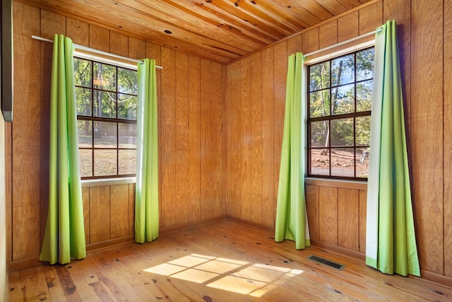 doorway featuring wood walls, light wood-type flooring, and wooden ceiling