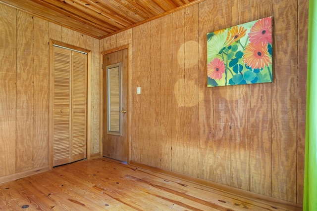 empty room featuring wood-type flooring, wood ceiling, and wooden walls