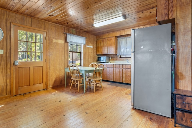 kitchen featuring wooden ceiling, light wood-type flooring, wooden walls, and appliances with stainless steel finishes