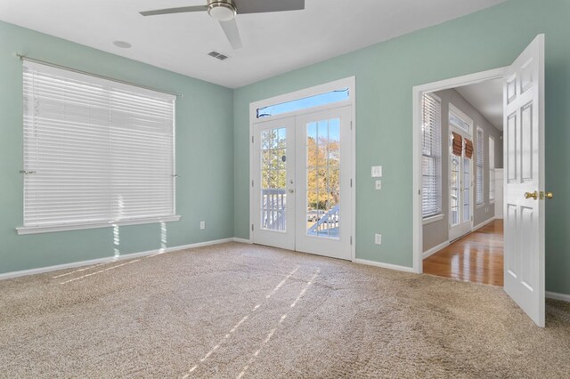 carpeted empty room with ceiling fan, a wealth of natural light, and french doors