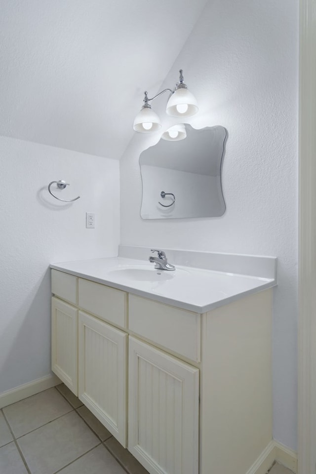 bathroom with tile patterned flooring, vaulted ceiling, and vanity