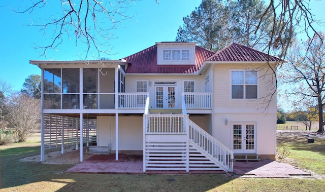 rear view of house with a patio area, a sunroom, a lawn, and french doors