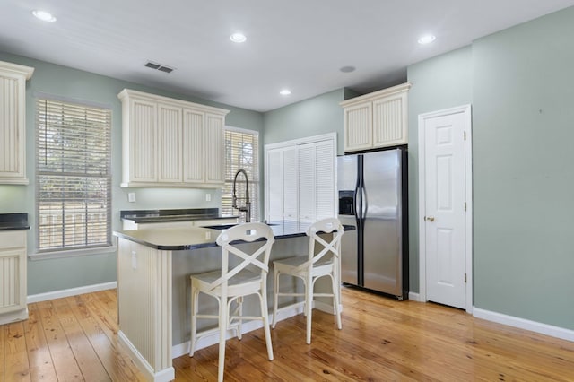 kitchen featuring sink, light hardwood / wood-style flooring, a center island, and stainless steel fridge