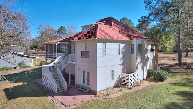 view of side of home featuring a sunroom and a lawn