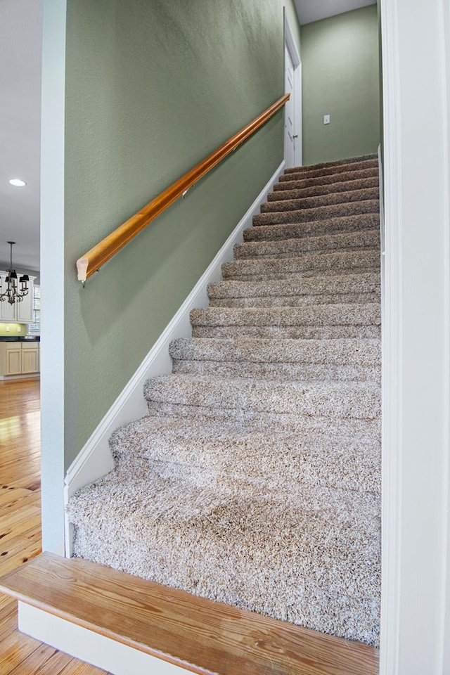 stairway featuring hardwood / wood-style floors and a notable chandelier