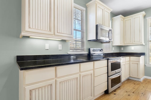 kitchen with light hardwood / wood-style floors, stainless steel appliances, and cream cabinets