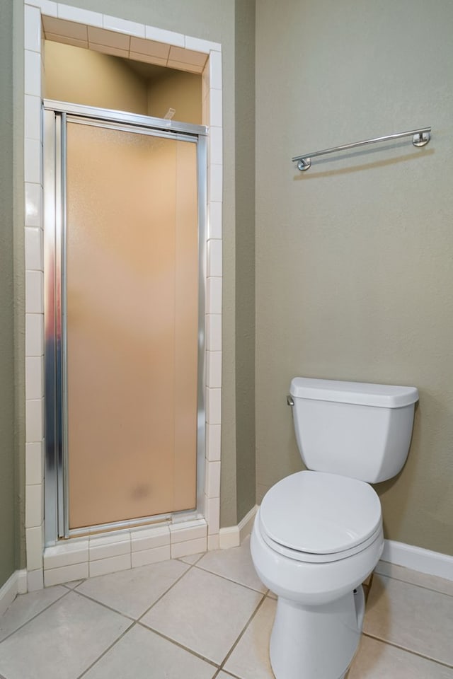 bathroom with toilet, a shower with door, and tile patterned flooring