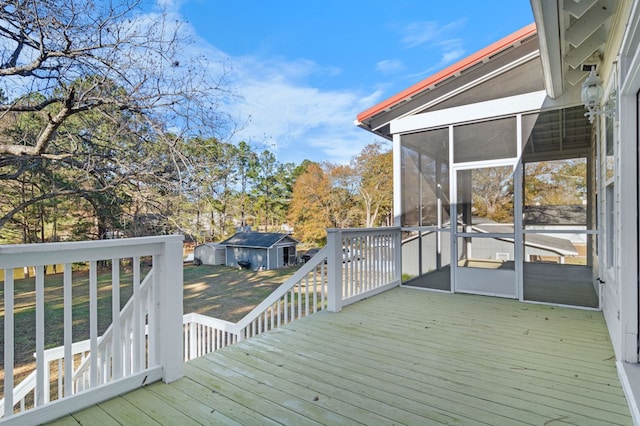 deck featuring a sunroom, a storage shed, and a yard