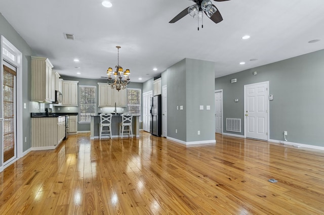 kitchen featuring pendant lighting, a center island, a kitchen bar, stainless steel appliances, and light hardwood / wood-style floors