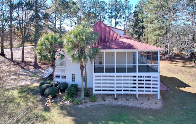 view of side of home with a sunroom and a yard