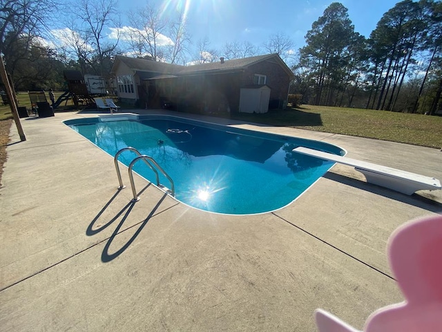 view of swimming pool featuring a patio, a yard, and a diving board