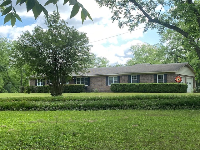 ranch-style house featuring brick siding, a front yard, and an attached garage