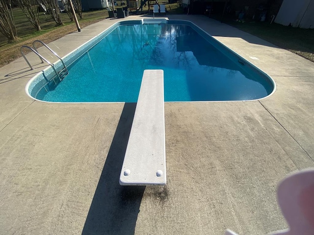 pool with a diving board and a patio area
