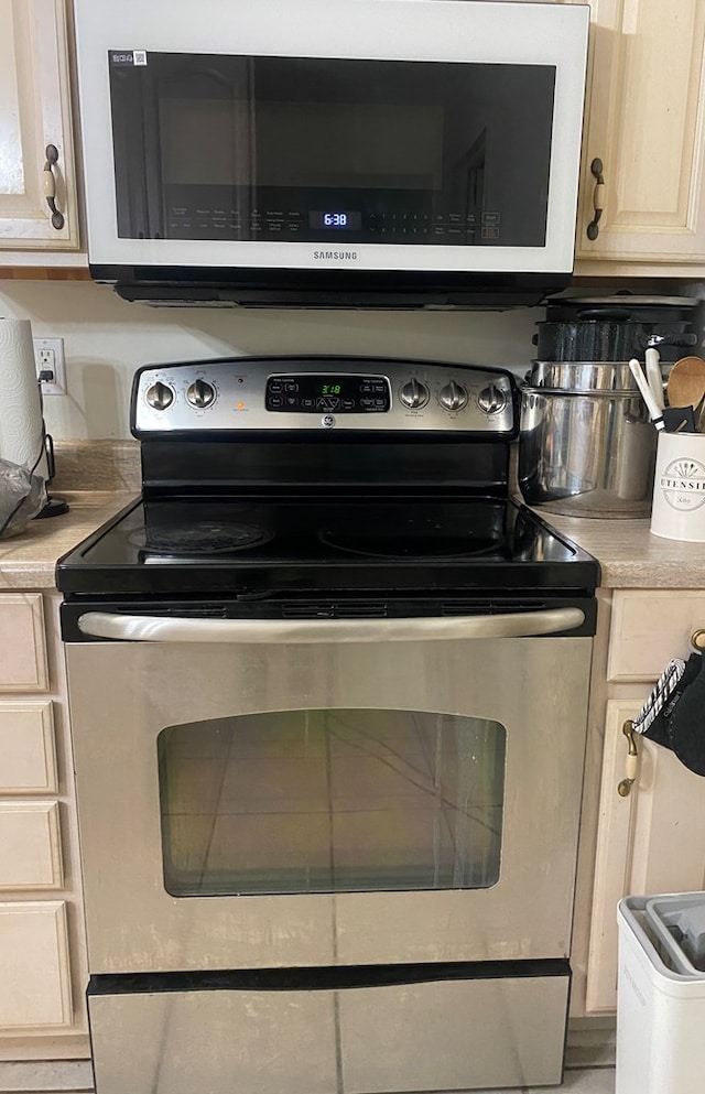 details with stainless steel electric range and light brown cabinets