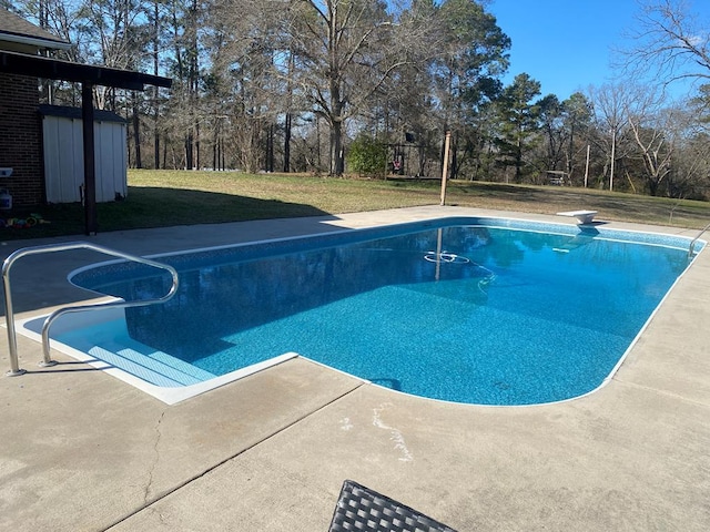 outdoor pool featuring a lawn, a storage unit, a patio, and an outbuilding