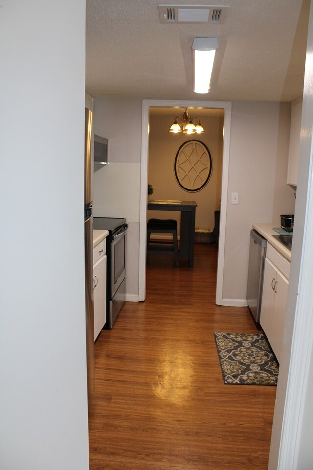 101F Country Club Dr, Americus, GA 31709 - kitchen with stainless steel appliances, light wood-style flooring, white cabinetry, a chandelier, and light countertops