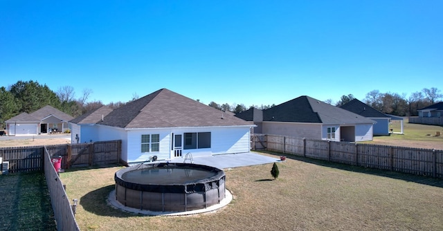 rear view of house featuring a fenced in pool and a yard