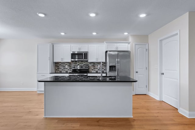 kitchen featuring white cabinetry, stainless steel appliances, sink, a kitchen island with sink, and light wood-type flooring