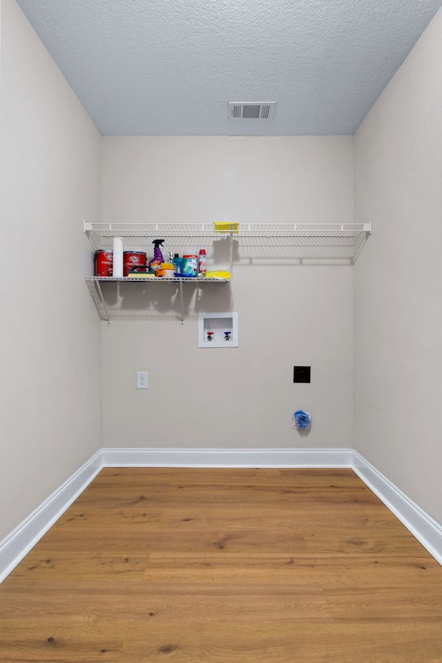 laundry area featuring hardwood / wood-style floors, a textured ceiling, and hookup for a washing machine