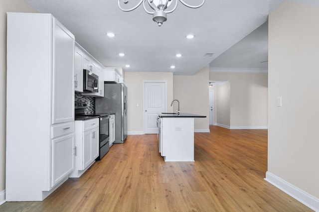 kitchen featuring light hardwood / wood-style flooring, backsplash, white cabinets, a kitchen island with sink, and stainless steel appliances