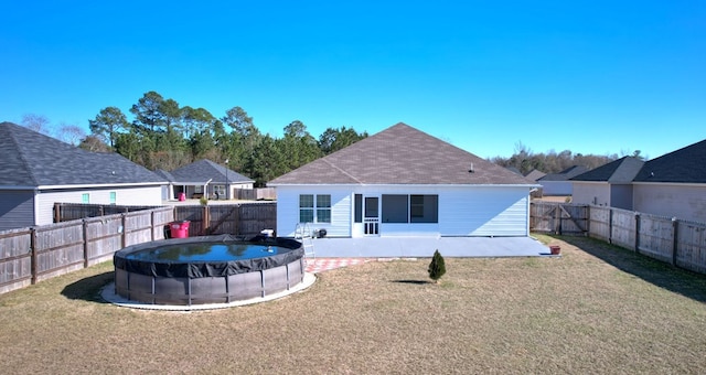 rear view of property featuring a covered pool and a yard