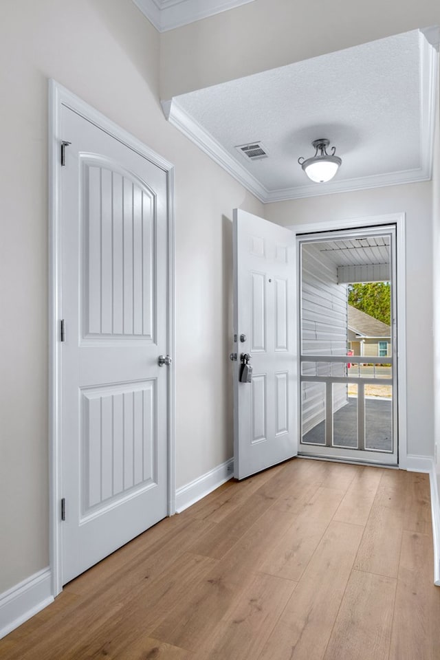 foyer with crown molding, light hardwood / wood-style flooring, and a textured ceiling