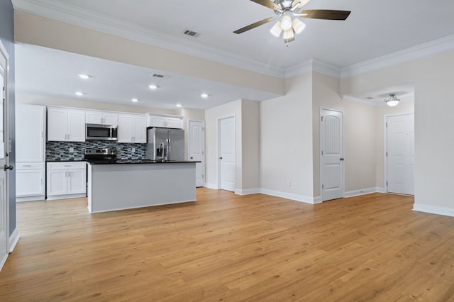 kitchen featuring light hardwood / wood-style flooring, appliances with stainless steel finishes, tasteful backsplash, white cabinetry, and a kitchen island