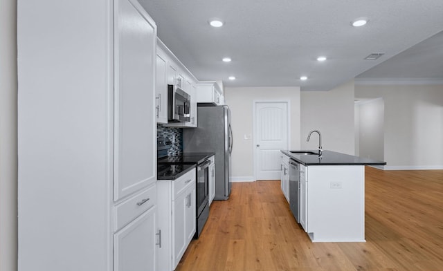 kitchen featuring a textured ceiling, white cabinetry, a kitchen island with sink, sink, and stainless steel appliances