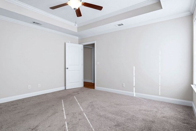 unfurnished room featuring ornamental molding, carpet floors, ceiling fan, and a raised ceiling