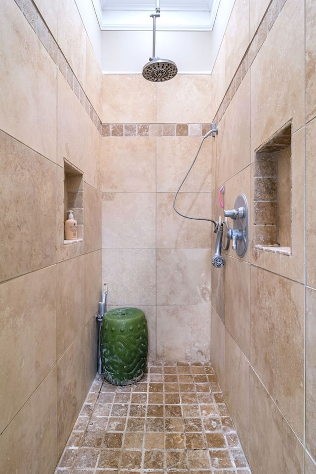 bathroom with ornamental molding and a tile shower