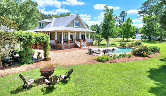 rear view of house with a patio, a lawn, covered porch, and a fire pit