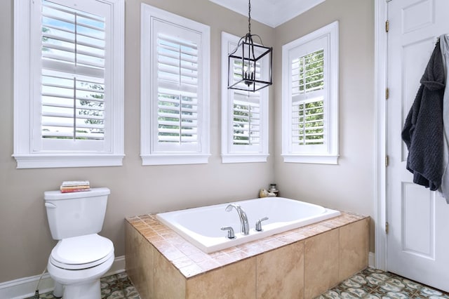 bathroom with tiled tub, a notable chandelier, plenty of natural light, and toilet