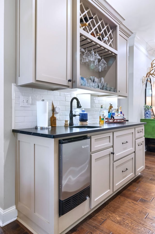 bar featuring backsplash, dark wood-type flooring, ornamental molding, and sink