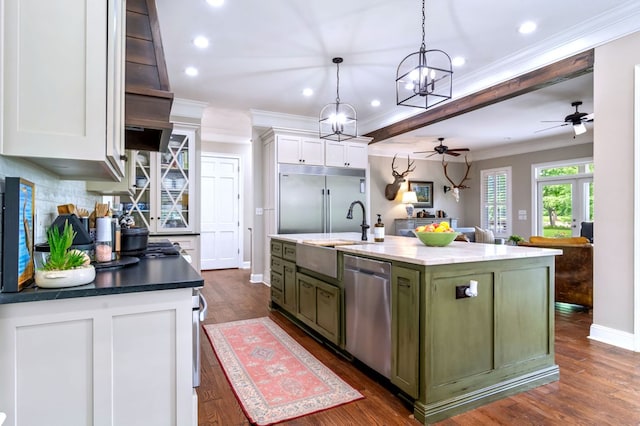 kitchen featuring green cabinets, hanging light fixtures, stainless steel appliances, white cabinets, and a center island with sink