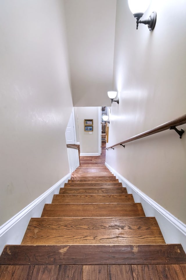 staircase with a towering ceiling and wood-type flooring