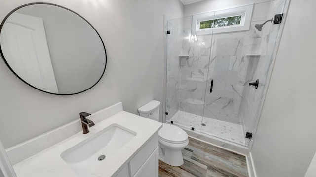 bathroom with a marble finish shower, toilet, vanity, and wood finished floors