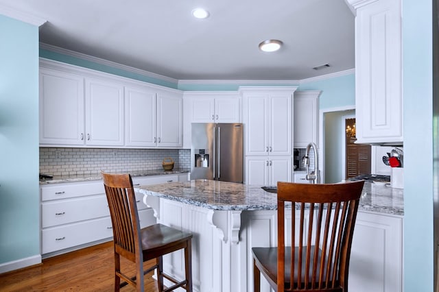 kitchen featuring light stone countertops, visible vents, white cabinetry, and stainless steel fridge with ice dispenser